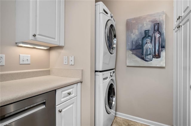 clothes washing area featuring cabinets and stacked washing maching and dryer