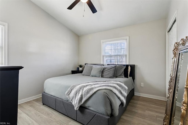 bedroom with ceiling fan, light hardwood / wood-style floors, and vaulted ceiling