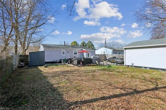 rear view of property featuring a yard and a storage unit