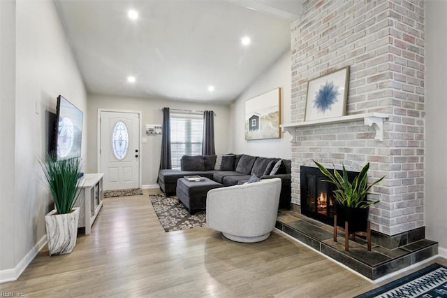 living room featuring hardwood / wood-style floors, vaulted ceiling, and a fireplace