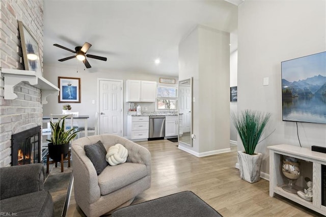 living room featuring a fireplace, light hardwood / wood-style floors, and ceiling fan