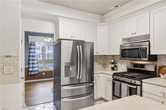 kitchen with ornamental molding, stainless steel appliances, decorative backsplash, and white cabinets