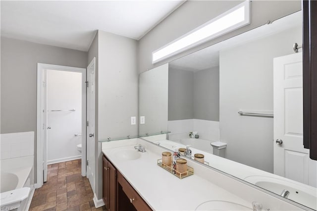 bathroom with vanity, a bath, and toilet