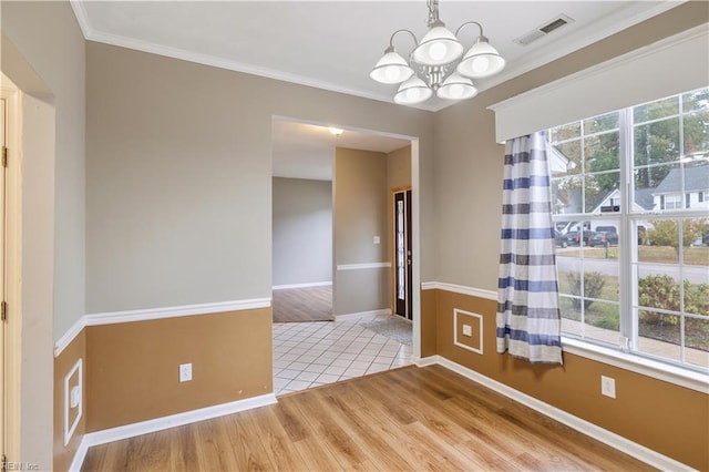 spare room featuring hardwood / wood-style flooring, ornamental molding, and a chandelier