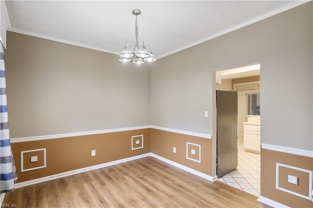 spare room featuring crown molding, a notable chandelier, and light hardwood / wood-style flooring