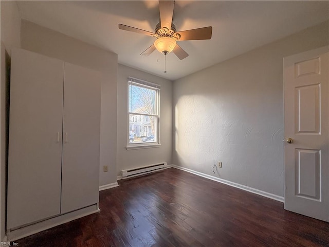 unfurnished bedroom featuring ceiling fan, a baseboard heating unit, and dark hardwood / wood-style flooring