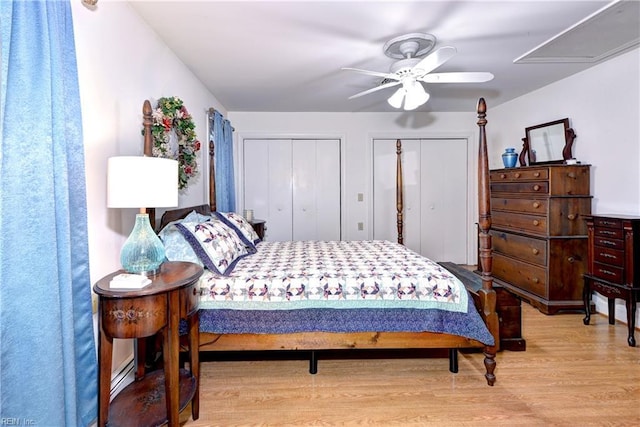 bedroom featuring ceiling fan, light hardwood / wood-style flooring, a baseboard radiator, and multiple closets