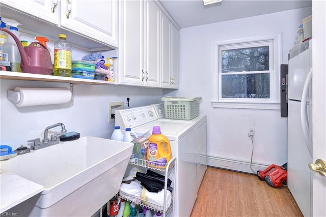 washroom featuring sink, baseboard heating, cabinets, light hardwood / wood-style floors, and separate washer and dryer