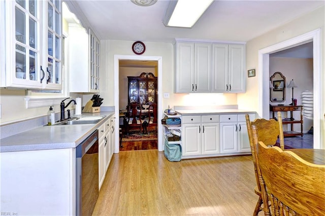 kitchen featuring stainless steel dishwasher, sink, light hardwood / wood-style flooring, and white cabinets