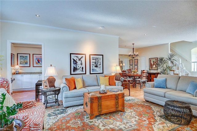 living room featuring ornamental molding, a chandelier, and light hardwood / wood-style flooring