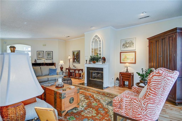 living room featuring crown molding, light hardwood / wood-style floors, and a textured ceiling