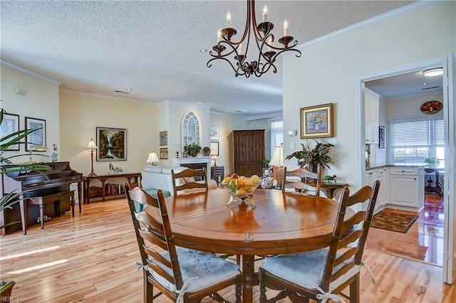 dining room featuring crown molding, a textured ceiling, and light hardwood / wood-style floors