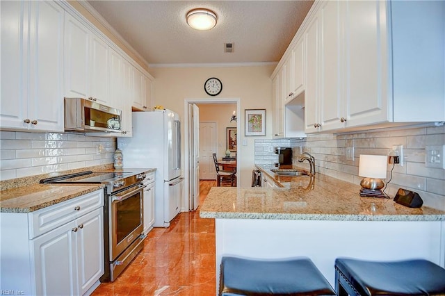 kitchen with sink, a breakfast bar area, white cabinetry, kitchen peninsula, and stainless steel appliances