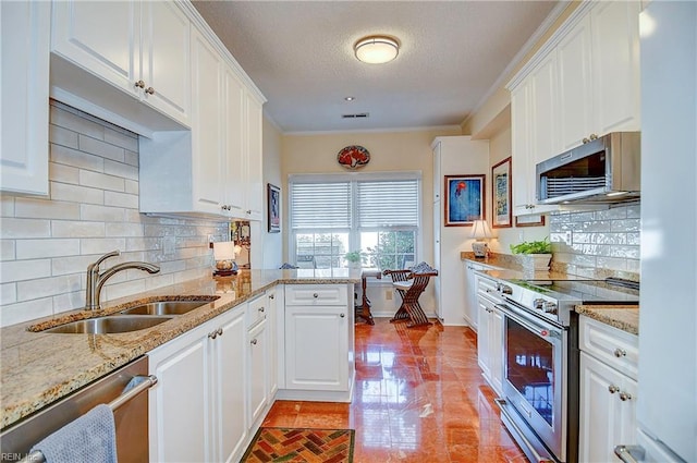 kitchen featuring sink, light stone counters, appliances with stainless steel finishes, kitchen peninsula, and white cabinets