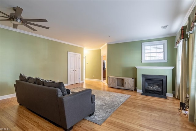 living room with crown molding, ceiling fan, and light hardwood / wood-style flooring