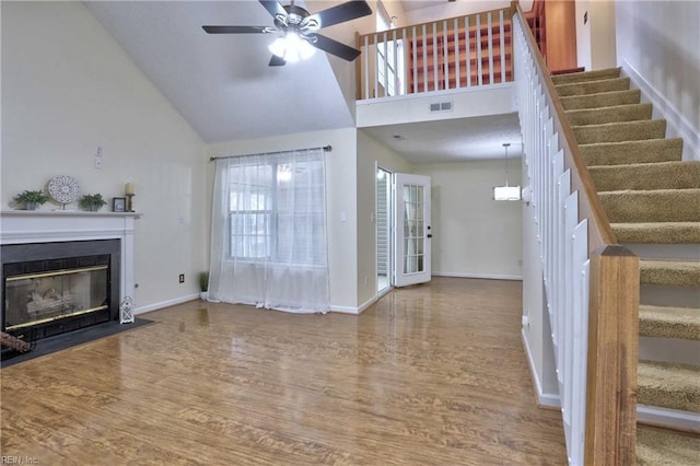 unfurnished living room with hardwood / wood-style flooring, ceiling fan, and high vaulted ceiling