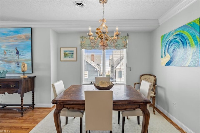 dining area with hardwood / wood-style flooring, ornamental molding, a chandelier, and a textured ceiling