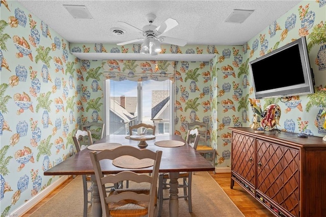 dining room featuring ceiling fan, a textured ceiling, and light hardwood / wood-style flooring