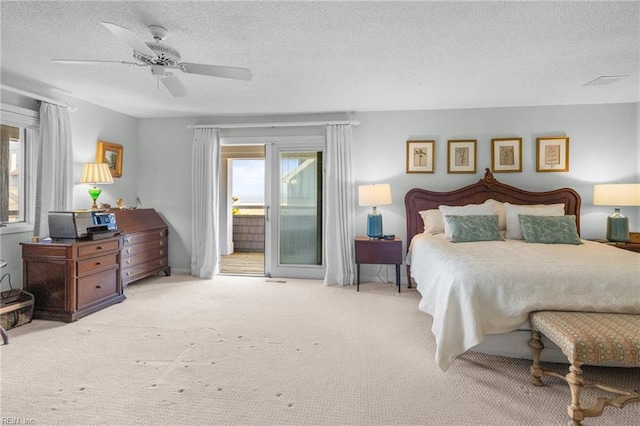 bedroom featuring ceiling fan, light carpet, a textured ceiling, and access to outside