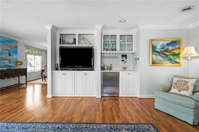 living room with hardwood / wood-style floors, ornamental molding, a textured ceiling, and indoor bar