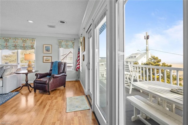 interior space featuring crown molding, a textured ceiling, and light hardwood / wood-style floors