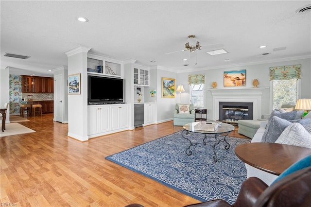 living room featuring hardwood / wood-style flooring, ceiling fan, and ornamental molding