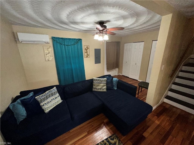 living room featuring ceiling fan, a wall mounted air conditioner, dark hardwood / wood-style floors, and electric panel