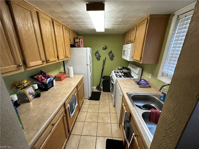 kitchen featuring sink, white appliances, and light tile patterned flooring