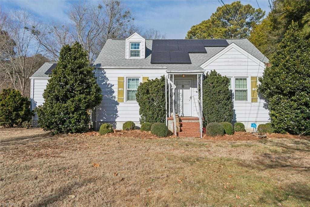 new england style home featuring a front lawn and solar panels