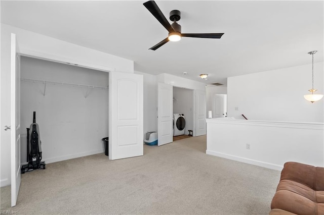 interior space with ceiling fan, washer / dryer, and light carpet