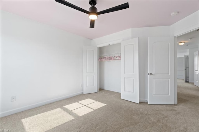 unfurnished bedroom with light colored carpet, a closet, and ceiling fan