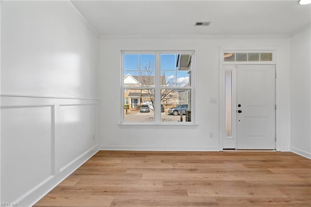 entrance foyer featuring ornamental molding and light wood-type flooring