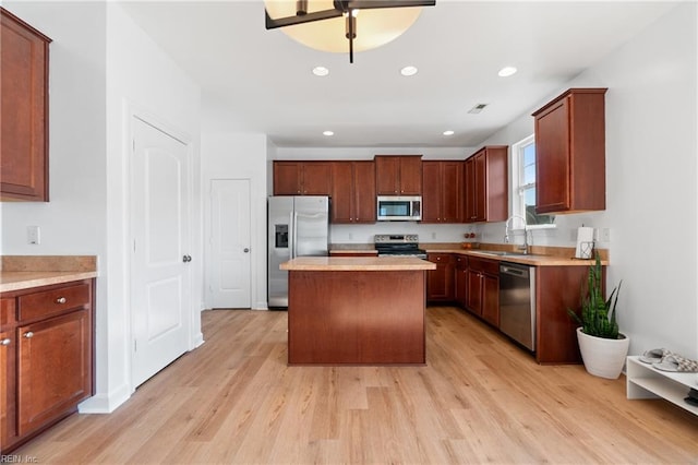 kitchen with light wood-type flooring, sink, a kitchen island, and appliances with stainless steel finishes