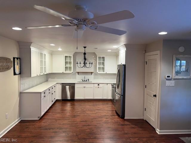 kitchen with dark wood-type flooring, stainless steel appliances, decorative backsplash, and white cabinets