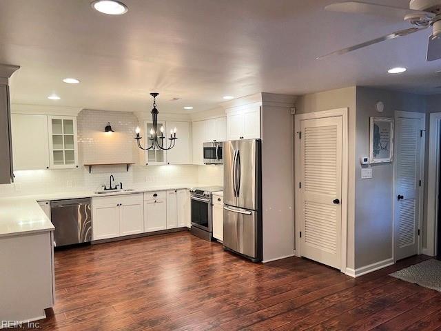 kitchen with appliances with stainless steel finishes, pendant lighting, white cabinets, and dark hardwood / wood-style flooring