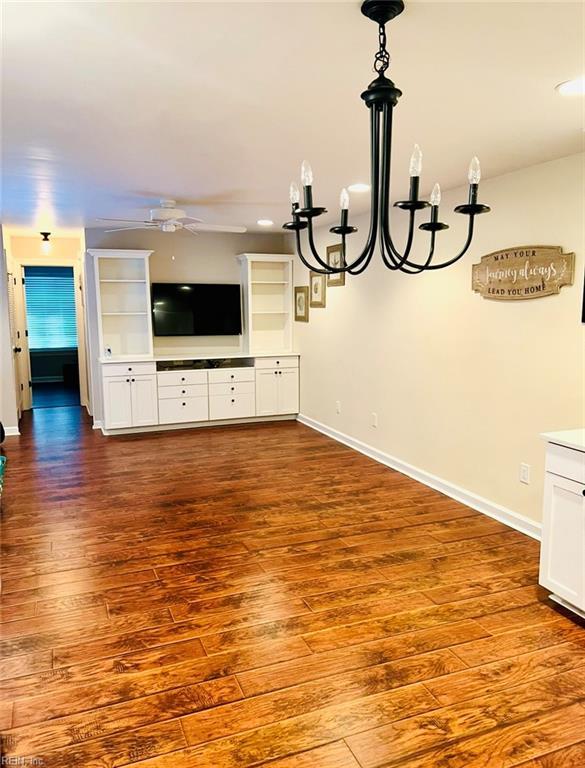 unfurnished living room with hardwood / wood-style flooring and ceiling fan with notable chandelier