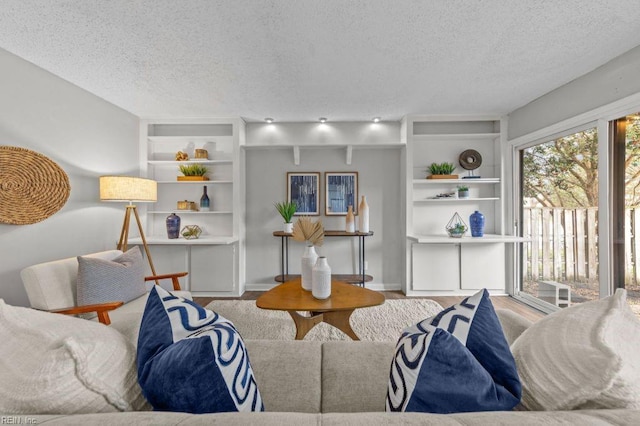 living room featuring wood-type flooring, built in features, and a textured ceiling