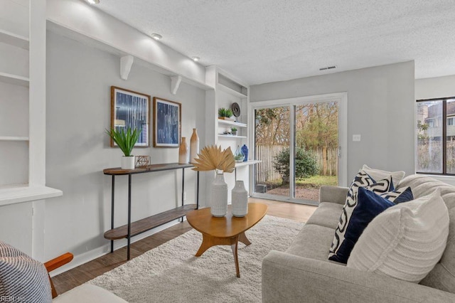 living room with hardwood / wood-style flooring, built in features, and a textured ceiling