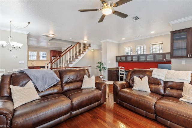 living room featuring crown molding, a wealth of natural light, dark hardwood / wood-style floors, and ceiling fan with notable chandelier