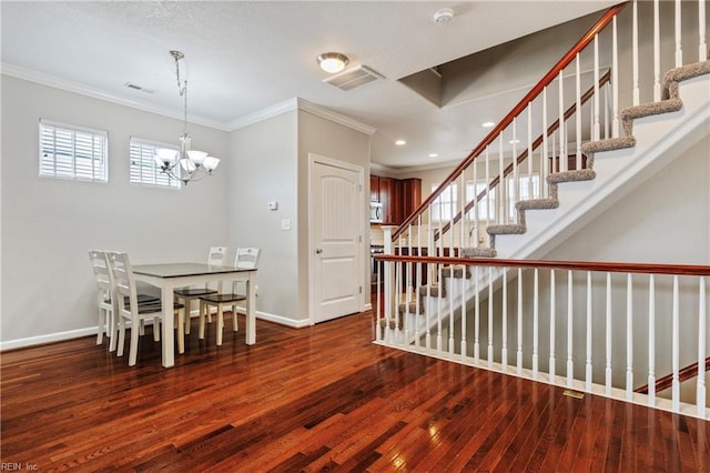 dining room featuring crown molding, hardwood / wood-style flooring, and an inviting chandelier