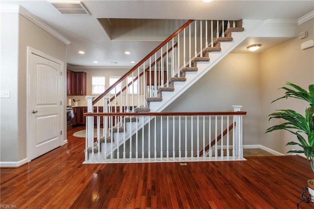 stairway with crown molding and wood-type flooring