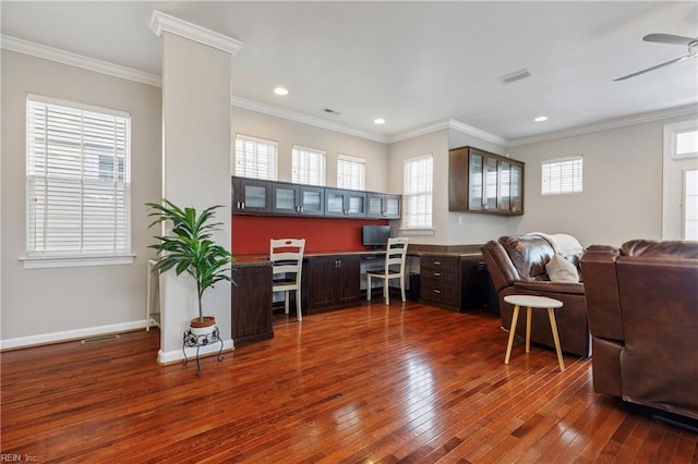 home office featuring ornamental molding, dark hardwood / wood-style floors, built in desk, and ceiling fan