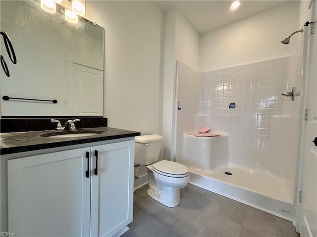 bathroom with a tile shower, vanity, and toilet