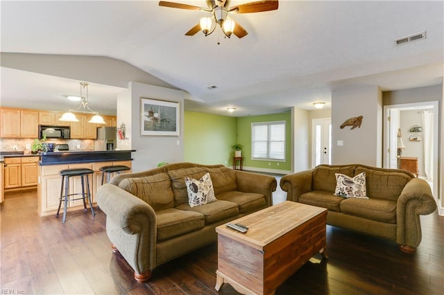 living room featuring vaulted ceiling, dark wood-type flooring, and ceiling fan with notable chandelier