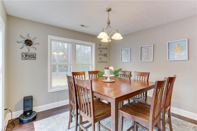 dining area featuring dark wood-type flooring and an inviting chandelier