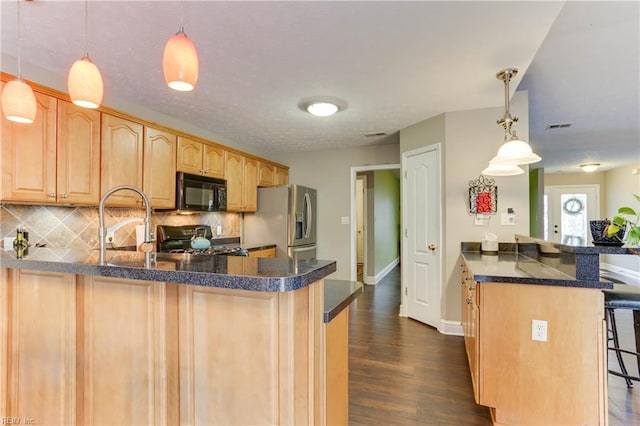 kitchen featuring range, stainless steel refrigerator with ice dispenser, a kitchen bar, light brown cabinetry, and decorative light fixtures