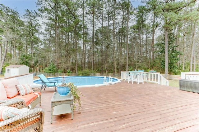 view of pool with a wooden deck, outdoor lounge area, and a storage shed