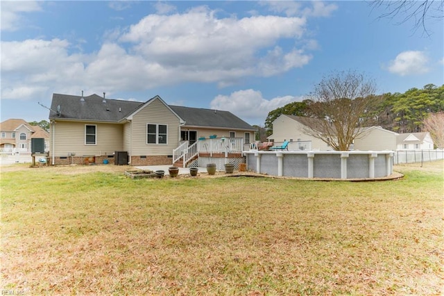 back of property with a swimming pool side deck and a yard