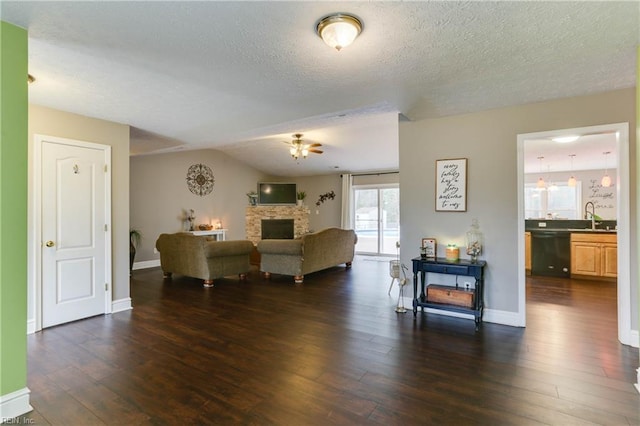 living room with lofted ceiling, a stone fireplace, dark hardwood / wood-style flooring, and sink