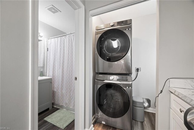 laundry room with stacked washer / dryer and dark wood-type flooring